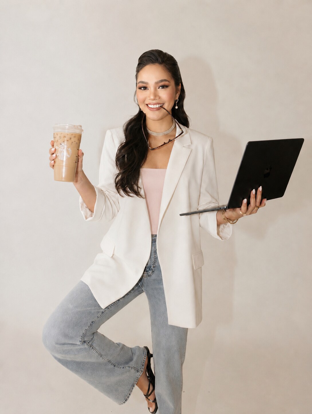Lanie smiling while holding an iced coffee and laptop